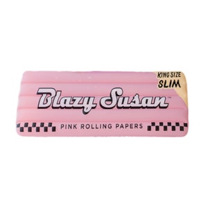 May include: Pink rolling papers with the text "Blazy Susan" and "King Size Slim" in white lettering. The papers have a checkered pattern on the bottom.