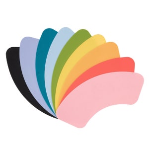 May include: A set of nine toilet seat covers in a rainbow of colors, including black, purple, blue, light blue, green, yellow, orange, red, and pink.