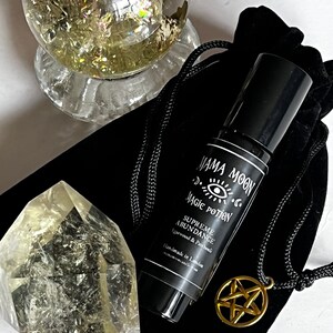 May include: A black velvet pouch containing a gold pentagram necklace and a black roll-on bottle labelled "Mama Moon Magic Potion Supreme Abundance Agarwood & Patchouli Handmade in London".