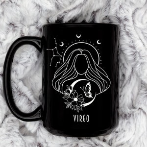 May include: Black ceramic mug with a white design of a woman with long hair, a crescent moon, a butterfly, and flowers. The text "VIRGO" is printed below the design.