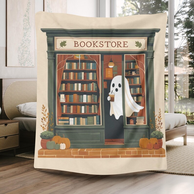 K&ouml;nnte beinhalten: Beige Decke mit einer Illustration eines Buchladens. Ein Geist mit einem Getr&auml;nk steht vor dem Buchladen. Das Wort "BOOKSTORE" steht &uuml;ber dem Eingang. K&uuml;rbisse und Pflanzen befinden sich am Fu&szlig;e des Ladens. Der T&uuml;rrahmen ist gr&uuml;n.