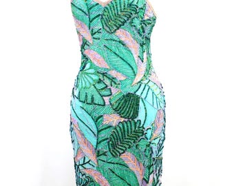 Può includere: Un abito midi senza maniche con un vivace motivo a foglie tropicali nei toni del verde smeraldo, verde chiaro e rosa tenue. L'intera superficie è ricoperta da intricate perline, con sottili spalline e uno spacco sull'orlo anteriore.