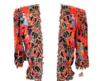 May include: An open-front jacket featuring a vibrant orange, black, and turquoise abstract print. The garment is adorned with intricate black and gold beaded floral embroidery along the front edges and sleeve cuffs, creating a textured finish.