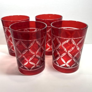 May include: Set of four red drinking glasses. Each glass features a diamond pattern etched into the glass. The glasses are a vibrant red color and are cylindrical in shape.