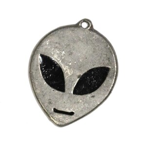 May include: A silver charm in the shape of an alien head with black eyes. The charm is a popular choice for jewelry making and is a fun and quirky addition to any collection.