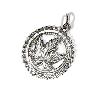 May include: Silver pendant charm featuring a detailed leaf design inside a circular frame.