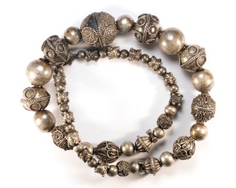 May include: A silver necklace with large, ornate beads. The beads are made of silver and have intricate designs. The necklace is a beautiful piece of jewelry that would make a great gift.