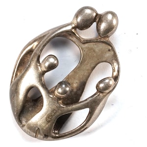 May include: A silver pendant depicting a family of four in an abstract, modern style. The figures are intertwined, symbolizing unity and love.
