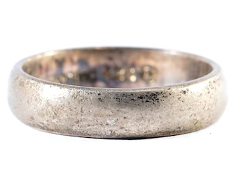 May include: A silver wedding band with a worn, textured finish.