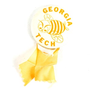 May include: A white button with a yellow bee and the text "Georgia Tech" in yellow letters.
