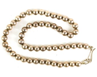 May include: A silver necklace with a chain of round beads and a silver clasp.
