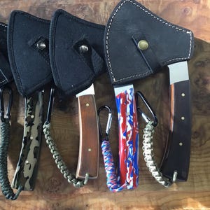 May include: Four small black leather sheaths with silver blades and colorful paracord lanyards. The sheaths have a snap closure and a loop for attaching a lanyard.