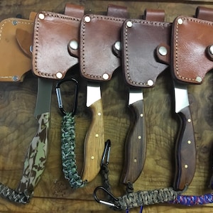 May include: Six small hand axes with leather sheaths and different colored handles. The handles are camouflage, wood, and blue and red marbled.