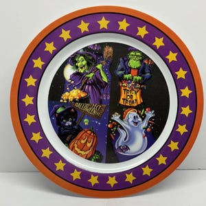 Pode incluir: Um prato redondo com tema de Halloween com uma borda laranja e uma faixa roxa com estrelas amarelas. O centro tem quatro ilustrações de desenhos animados de uma bruxa, o monstro de Frankenstein, um gato preto e um fantasma. O prato tem as palavras "Trick or Treat" e "Halloween!!!".