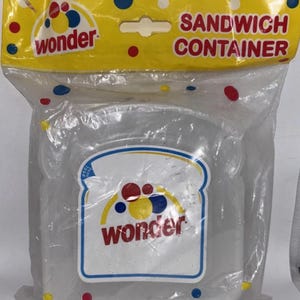 May include: A clear plastic sandwich container in a sealed plastic bag. The container has a white and blue label with the word "wonder" and a bread slice design. The bag has the words "SANDWICH CONTAINER".