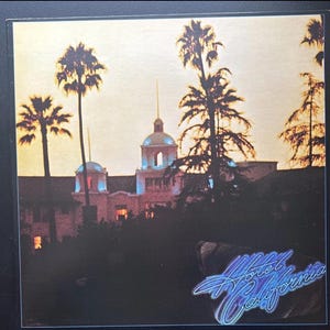 Könnte beinhalten: Albumcover mit einem Gebäude mit Kuppeldach und Palmen vor einem Sonnenuntergang. Der Titel "Hotel California" ist in einer stilisierten, neonartigen Schrift in der unteren rechten Ecke geschrieben. Das Farbschema ist warm, mit Orange- und Blautönen.
