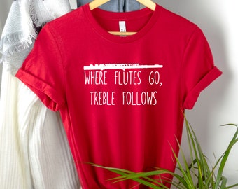 Peut inclure: T-shirt rouge avec un graphique blanc d'une flûte et le texte "Where Flutes Go, Treble Follows".