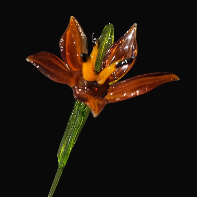 オレンジ色の焦げたガラスのユリ、手作りのガラスの花、ウクライナで