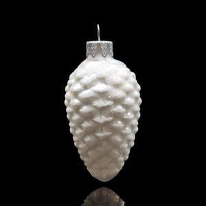 May include: White glass Christmas ornament shaped like a pine cone with a glittery finish.