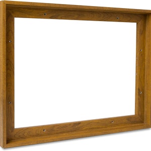 Puede incluir: Un marco de madera rectangular con un acabado marr&oacute;n c&aacute;lido. El marco tiene un dise&ntilde;o sencillo y limpio con vetas de madera visibles y agujeros pre-perforados para el montaje. El marco est&aacute; vac&iacute;o, con un fondo blanco visible a trav&eacute;s de la abertura.
