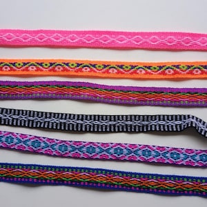 Peut inclure: Cinq galons tissés colorés avec des motifs géométriques. Les galons sont dans des tons de rose, orange, violet, noir, bleu et vert.