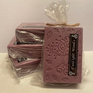 May include: A stack of five purple soap bars wrapped in clear plastic. The top bar has a decorative design of a tree with leaves and the text "Twilight Woods".