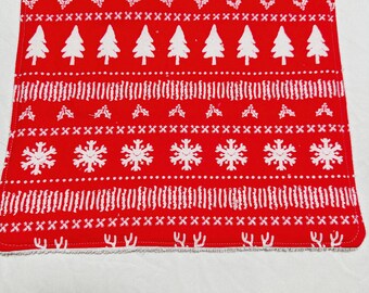 May include: Red fabric kitchen dishcloth with a white Christmas pattern of trees, snowflakes, and holly. The dishcloth has a frayed edge.