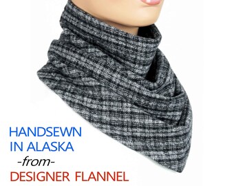 May include: A black and white checkered flannel neck warmer. The neck warmer is hand-sewn in Alaska. The text "HANDSEWN IN ALASKA -from- DESIGNER FLANNEL" is printed below the neck warmer.