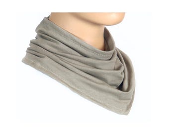 May include: A light brown neck gaiter made of soft fabric. The gaiter is folded and has a seam around the edge.