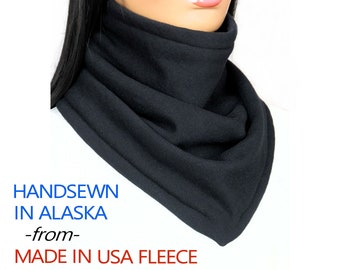 May include: Black fleece neck warmer, handmade in Alaska.  The neck warmer is folded and has a seam around the edge.  The text "HANDSEWN IN ALASKA -from- MADE IN USA FLEECE" is printed below the neck warmer.
