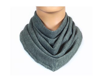 May include: A gray knitted neck warmer or scarf. The scarf is folded and gathered to create a thick, cozy look.