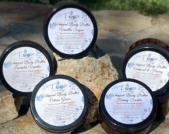 May include: Five jars of whipped body butter with different scents: Lavender Vanilla, Vanilla Sugar, Citrus Grove, Oatmeal & Honey, and Honey Suckle. Each jar has a white label with a floral design and the brand name "T. Louise Handmade Soaps".