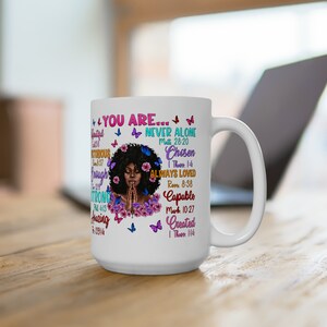 May include: White ceramic mug with a colorful design featuring a woman with her hands clasped in prayer. The design includes butterflies, flowers, and inspirational text with bible verses, including "You Are... Never Alone, Chosen, Always Loved, Capable, Created".