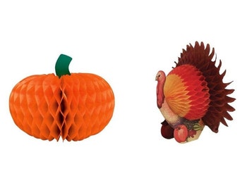 May include: Two paper decorations: an orange honeycomb pumpkin with a green stem and a turkey with red, orange, and brown tail feathers. The turkey has a beige body and is decorated with fruit.