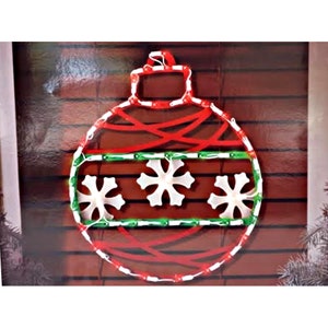 Peut inclure: Une décoration de Noël rouge et verte en forme de boule avec des flocons de neige blancs. La décoration est faite de lumières et est conçue pour être accrochée à un mur.