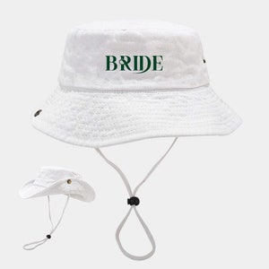 May include: White bucket hat with a green "BRIDE" text on the front. The hat has a black drawstring.