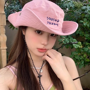 May include: A pink bucket hat with a black drawstring and the text "Forever! Go! Go!" embroidered on the front.