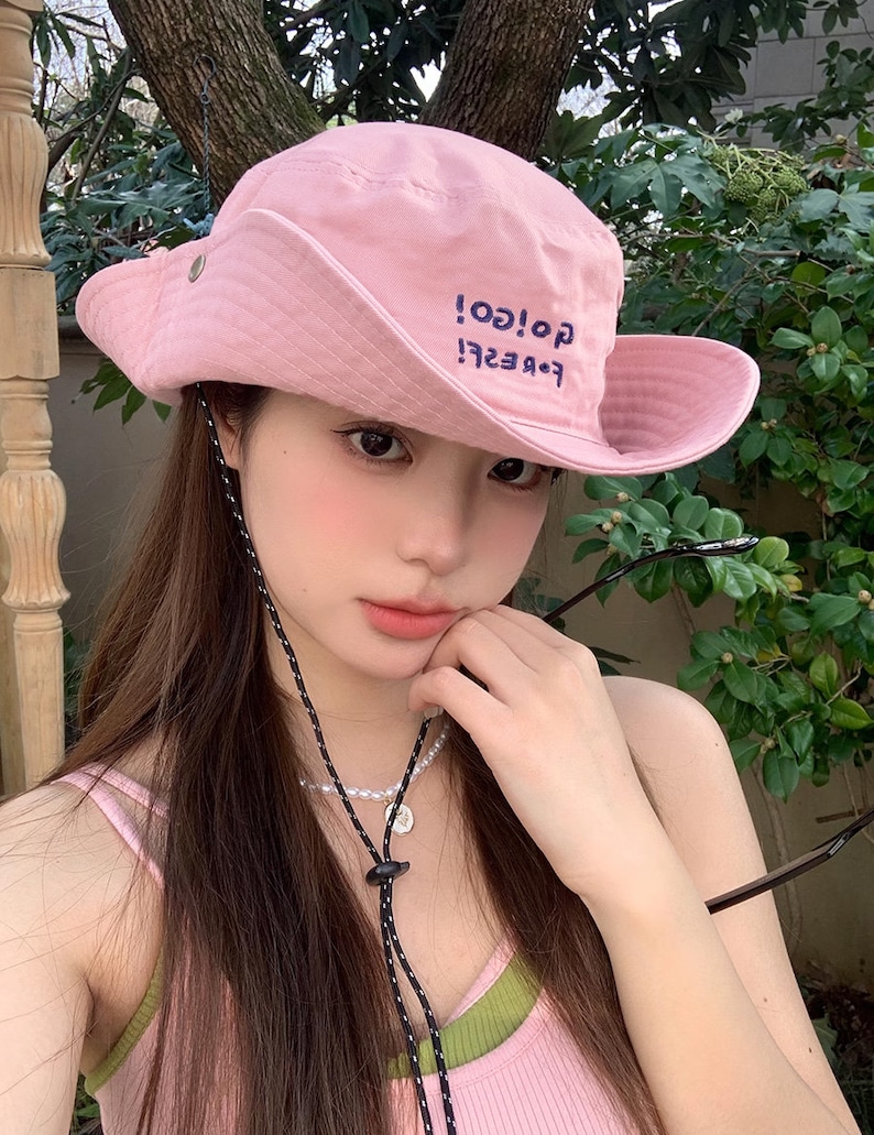 May include: A pink bucket hat with a black drawstring and the text "Forever! Go! Go!" embroidered on the front.