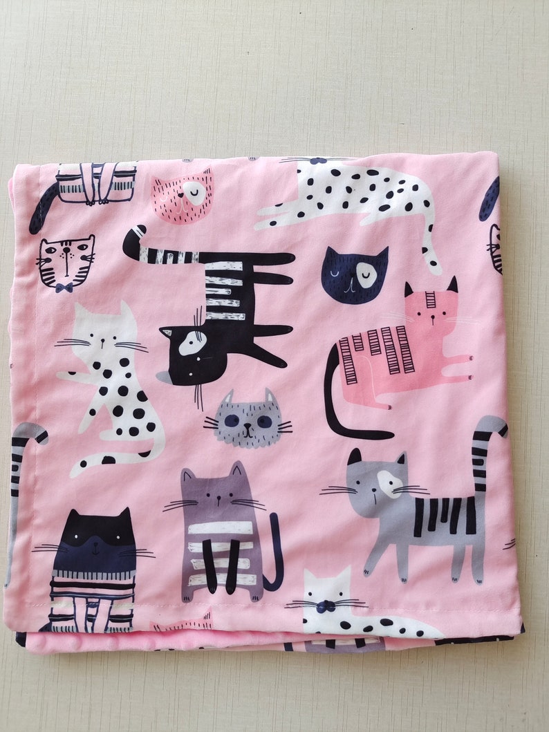 May include: Pink fabric with a repeating pattern of black and white cats. The cats are in various poses and have different facial expressions.