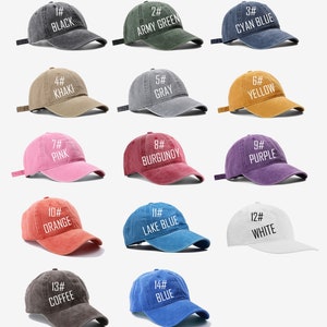 May include: A set of 14 different colored baseball caps with numbers and color names printed on them. The caps are arranged in four rows of three, with the last row having only two caps.