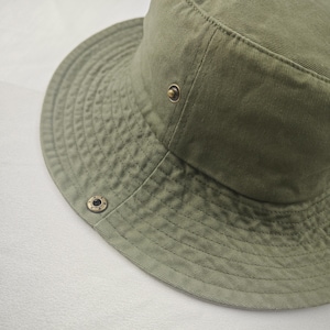 May include: A green canvas bucket hat with a brass button and grommet.
