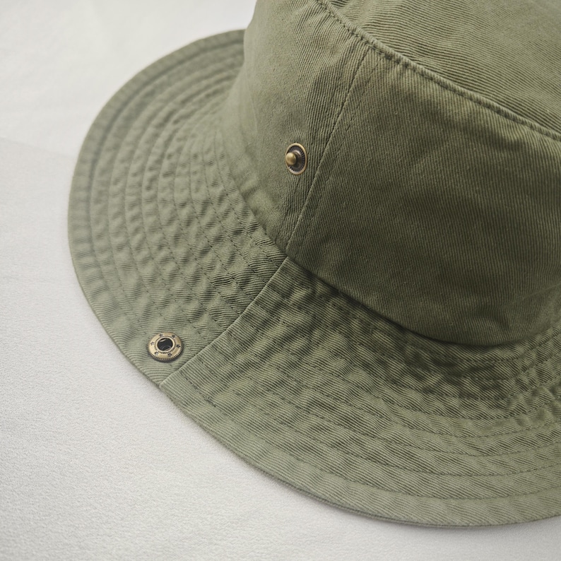 May include: A green canvas bucket hat with a brass button and grommet.