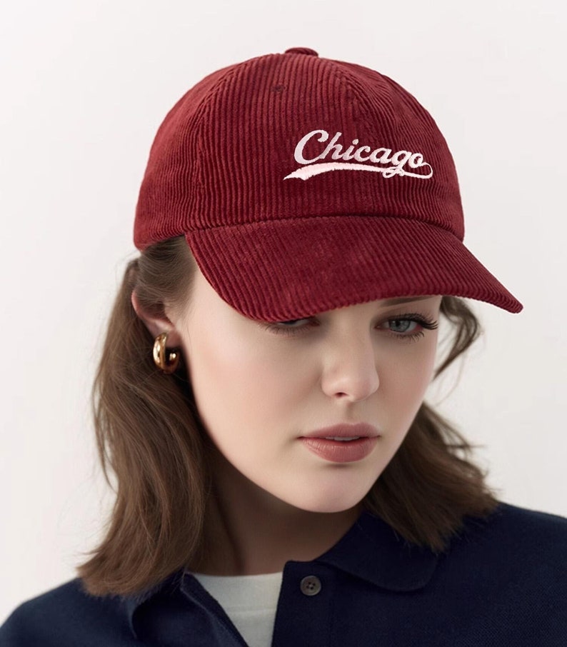 Puede incluir: Una gorra de b&eacute;isbol de pana roja con un logotipo "Chicago" bordado en blanco. La gorra tiene una visera curvada y una corona estructurada.