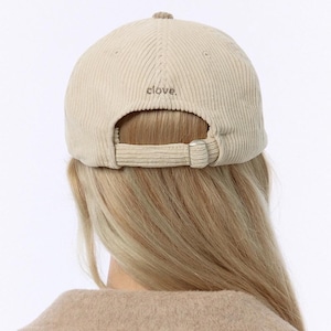 Puede incluir: Una gorra de b&eacute;isbol de pana beige con una correa ajustable y la palabra "Clove" bordada en la parte posterior.