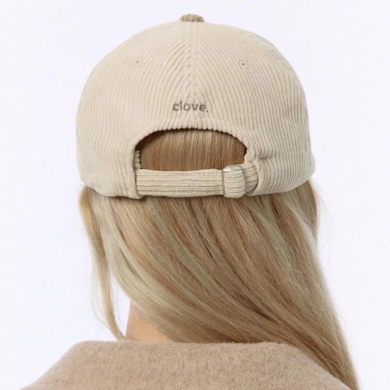 Puede incluir: Una gorra de b&eacute;isbol de pana beige con una correa ajustable y la palabra "Clove" bordada en la parte posterior.