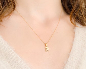 May include: A gold chain necklace with a small gold pendant in the shape of the letter "B".