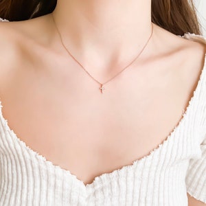 Puede incluir: Un delicado collar de oro con un peque&ntilde;o colgante de cruz brillante.