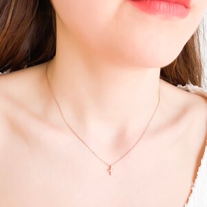 Puede incluir: Un delicado collar de cadena dorada con un peque&ntilde;o colgante de cruz brillante.