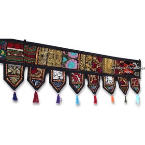 May include: A black fabric door hanging with colorful embroidered patches and tassels. The patches feature floral designs, geometric patterns, and gold accents. The hanging is approximately 30 inches long.