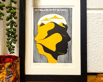 Peut inclure: Une estampe encadrée d'une illustration en noir et jaune d'un visage avec une chaîne de montagnes à l'intérieur de sa tête. L'estampe porte le texte "So I walked into the haze." en haut et est signée "Scots" et "Red" en bas.